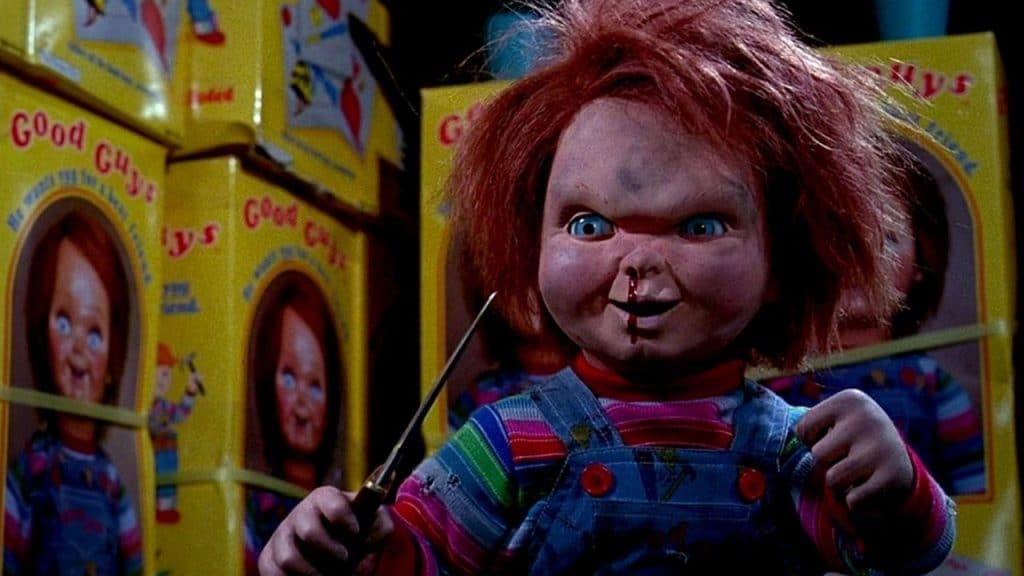 Imagem do filme exibe o boneco Chucky empunhando uma faca enquanto sai sangue de seu nariz.