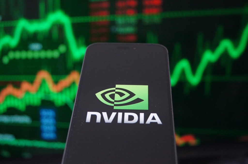 Logo da Nvidia em um smartphone com gráficos financeiros como plano de fundo desfocado